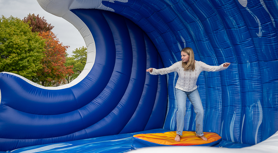 A student surfs on an inflatable wave during Family and Friends Weekend.