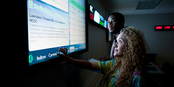 Students use a touchscreen to track investments.