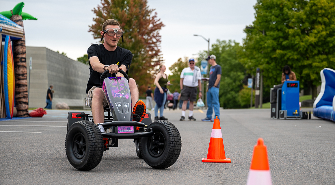 A student drives a kart around cones during Family and Friends Weekend.