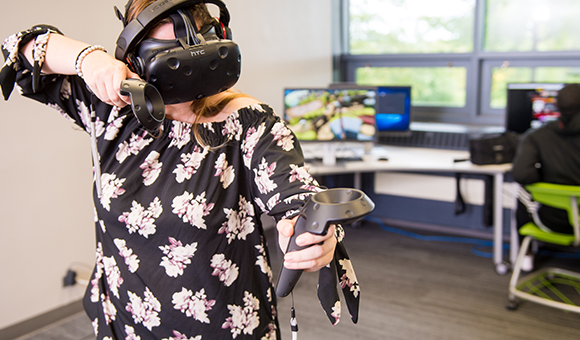 A female student plays a virtual reality game with HTC VR goggles.