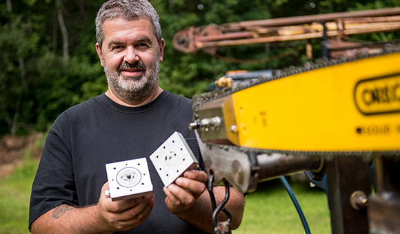 SUNY Canton Instructional Support Associate Neil A. Haney holds a working prototype of his chainsaw oiling invention 