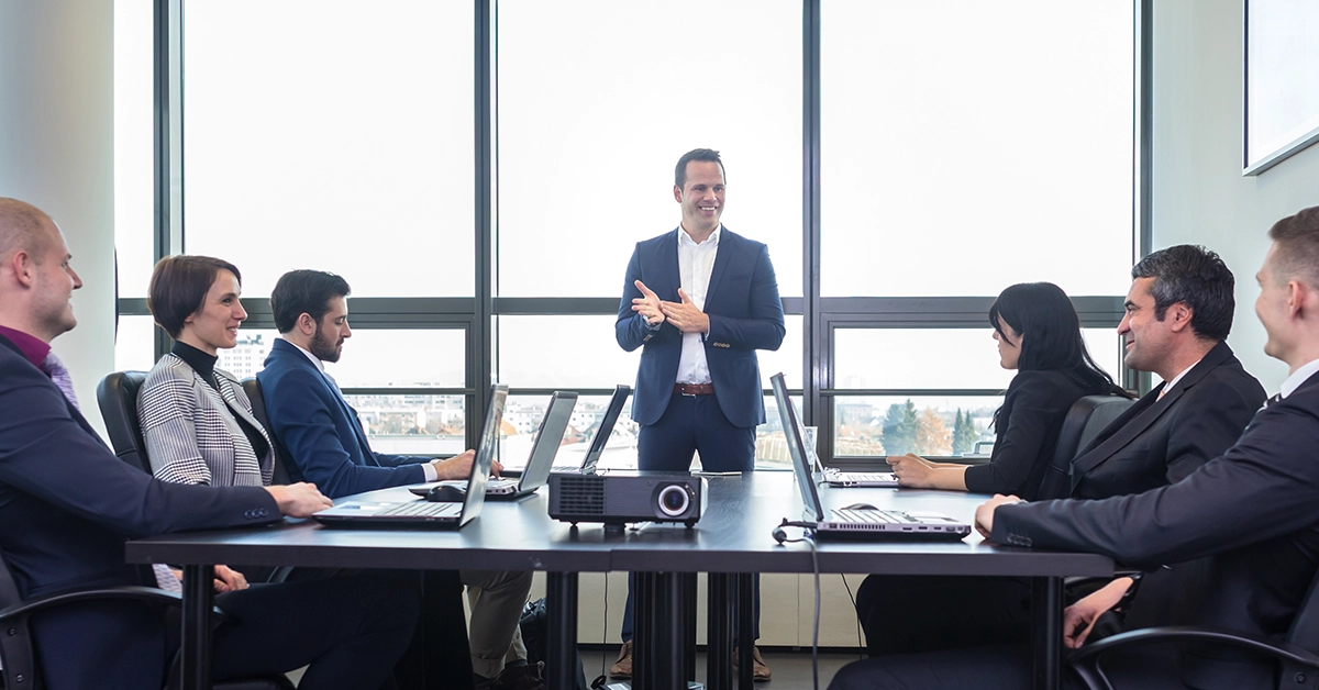 A manager speaks to a board room during a corporate meeting.