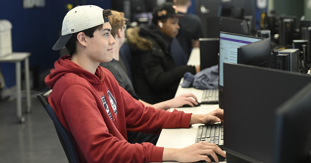 A student with a red hoodie works on a desktop computer in the Computer Information Systems lab.