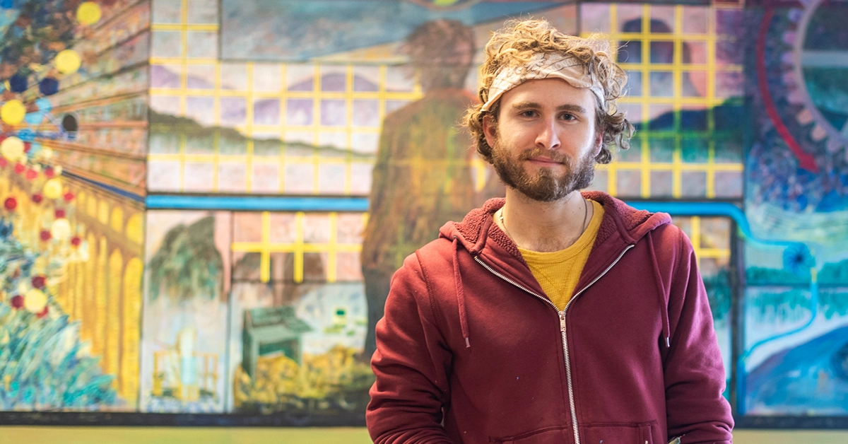 GMMD graduate Thomas Contino stands in front of his colorful mural.
