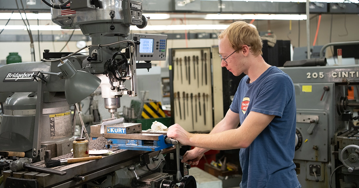 A student uses a drill press in the Mechanical Engineering Technology lab.