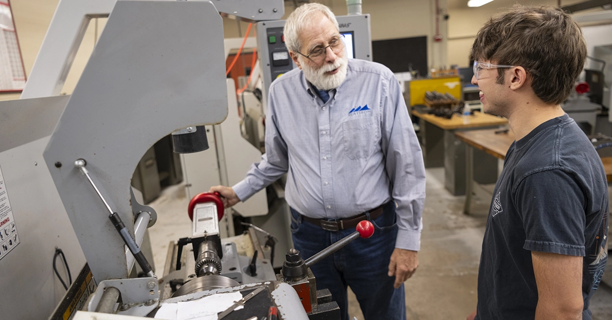 An instructor shows a student how to setup a CNC machine.