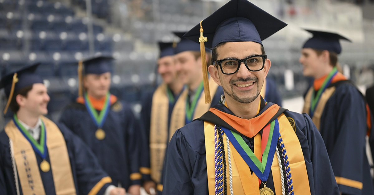 An honors graduate is all smiles in the ice arena before Commencement 2026.