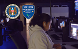 NSA and CJIC logos + A student types in the Cybersecurity lab.