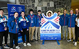 Sports Management student volunteers posing with a FISU University World Games display at Roos House.