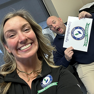 Jamie Burgess snaps a selfie of Corey Jordan holding a Giving Tuesday sign and making a silly face.