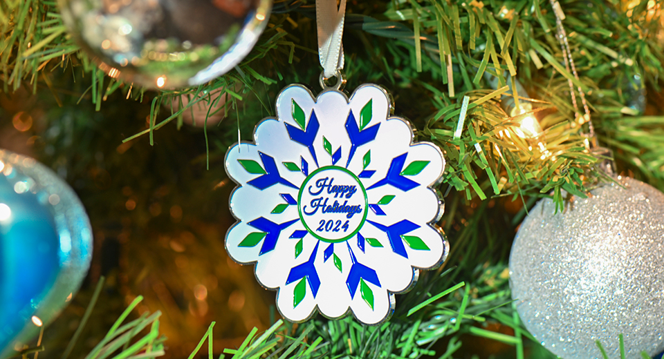 Happy Holidays! The 2024 decorative SUNY Canton ornament hangs from a tree.