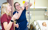 Two students set up an IV unit in the Nursing lab.