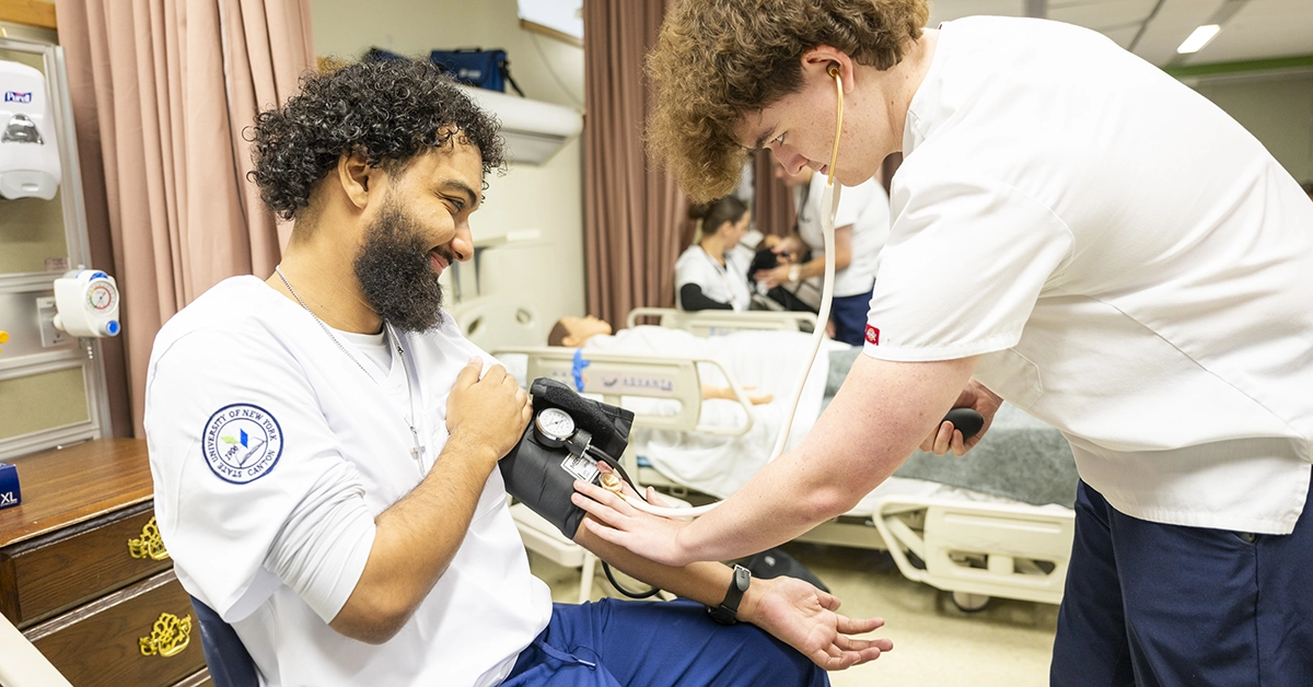 Two male nursing students practice taking blood pressure.