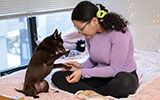A student plays with her puppy in a residence hall room.