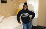 A student proudly stands in their single dorm room.