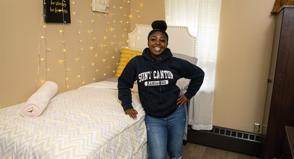 A student proudly stands in their single dorm room.