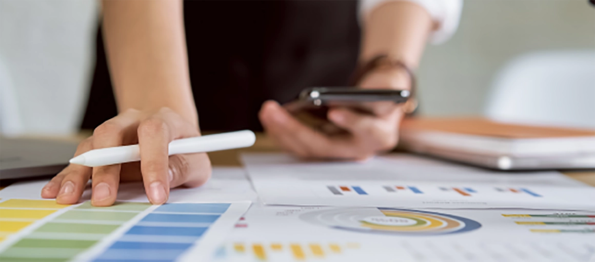 A person reviews a desktop full of analytics reports and marketing samples.