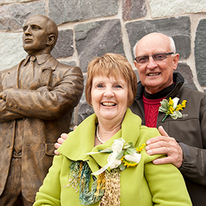 Terry and Jill Martin stand in front of the Terry Martin statue at the entrance of Roos House.