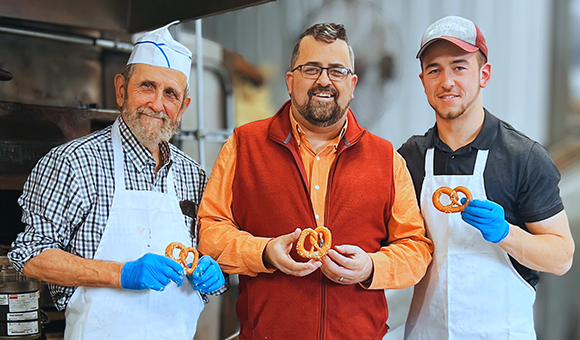 Lloyd, Justus, & Josiah Martin stand with pretzels on the grand-reopening in 2023!