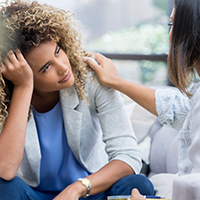 A person looks at a mental health counselor while being consoled.