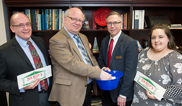 President Zvi Szafran draws cards as Provost Douglas Scheidt, Charles Fenner and Maria Vecchio pose for the photo.