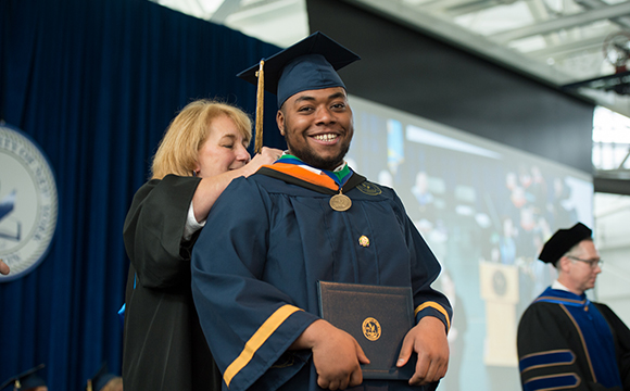 Kelly Obermeyer awards a graduate with a medallion.