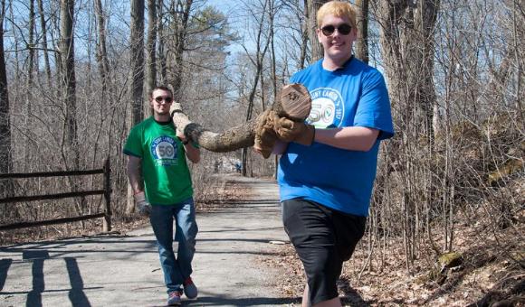 Students carry a log down a path at the Grasse River Heritage Park.