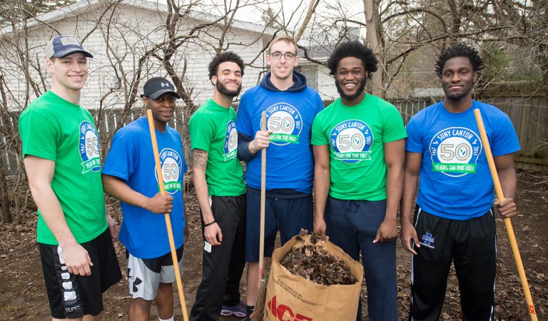 The Men's Basketball team poses in front of a bag of leaves.