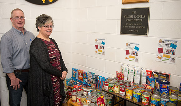 Physical Plant Director Patrick Hanss and Physical Plant Secretary Tammy Carr stand with the donations collected in Cooper Service Center for the food drive.