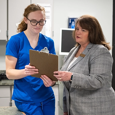 Two Nursing Home employees discuss plans from a clipboard.