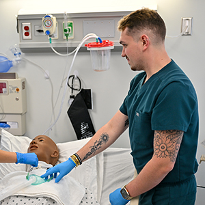 Jeremy Hebert works with one of the college’s computer-controlled interactive mannikins during a lab.