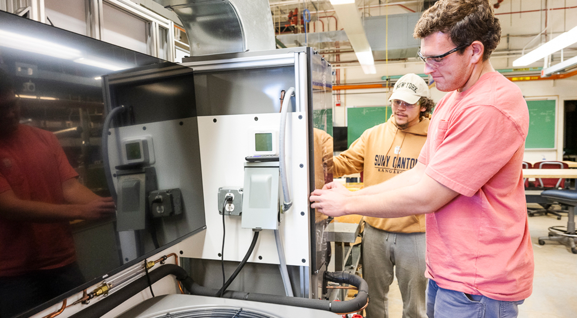 Two students work on a heat pump simulator in the HVAC lab.
