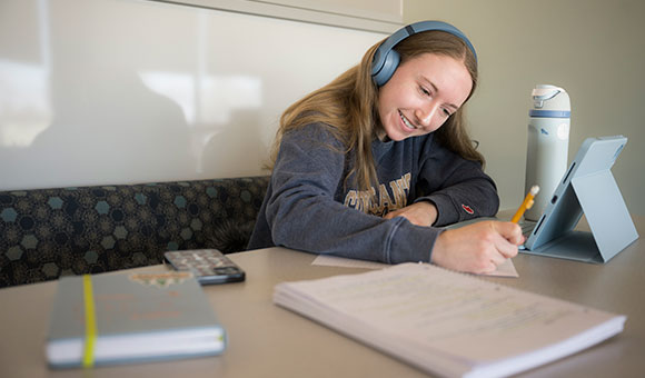 Colette Burger works online with headphones in Southworth library