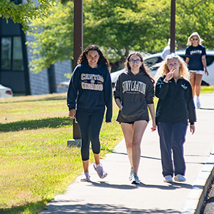 Three students walk down a sidewalk on a sunny move-in day at SUNY Canton.