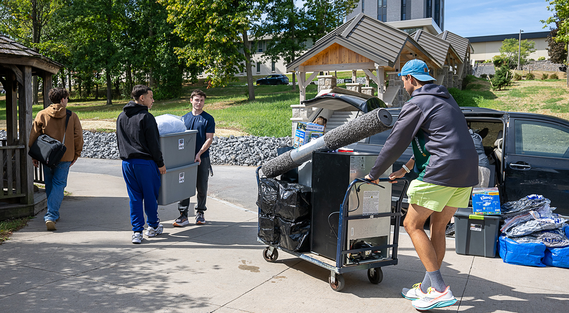 Students unload cars and use carts to move in to the residence halls.