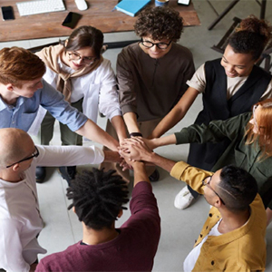 A group collectively puts their hands together in the middle of a circle.