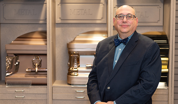 David Penepent stands in front of a casket array.