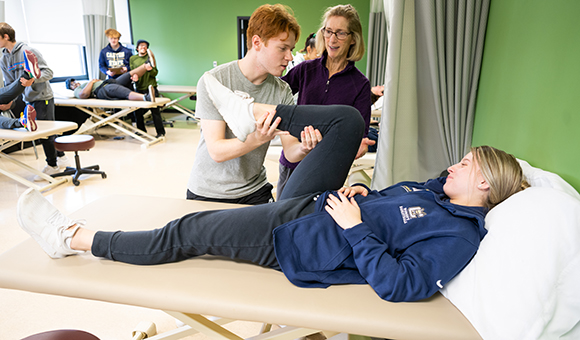 Anne Reilly assists a student with stretching a patient on a table.