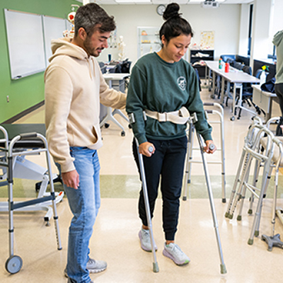 A student assists another student with crutches in the Physical Therapist lab.