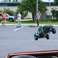 Three students launch an RC car off a ramp.