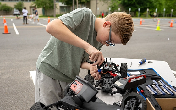 A camper repairs a remote controlled car on a table.