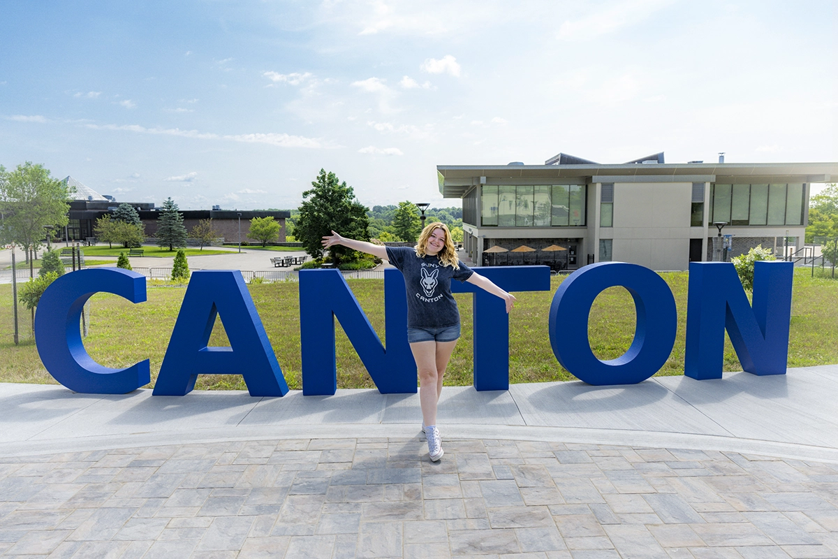 A Student Ambassador stands in front of large letters spelling out Canton in the new Roselle Plaza.