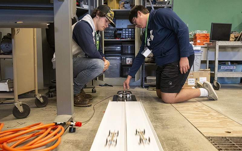 Two students race cars as part of the College for Every Student program.