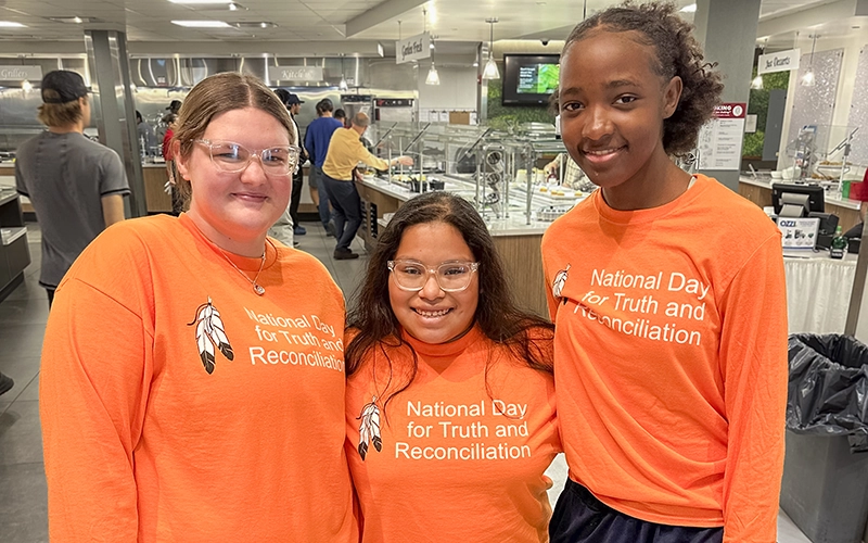 Three students wearing orange National Day for Truth and Reconciliation shirts in Chaney Dining Center.