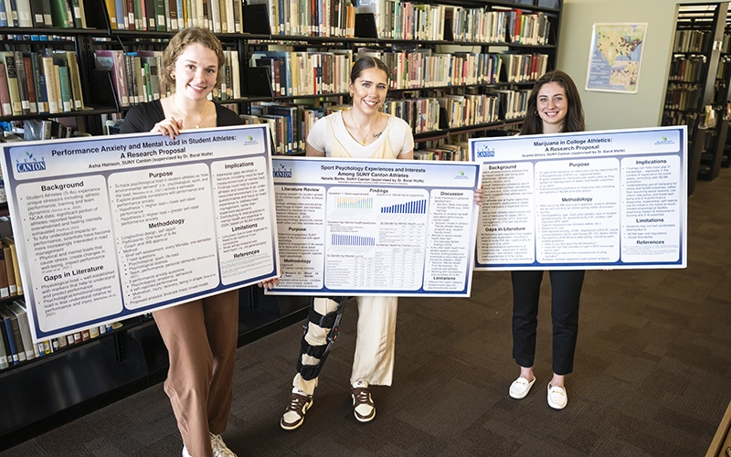 Three Psychology students show off their research posters at the Scholarly Activities Fair.