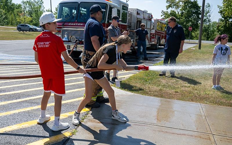 Campers spray a fire hose outside Dana Hall.