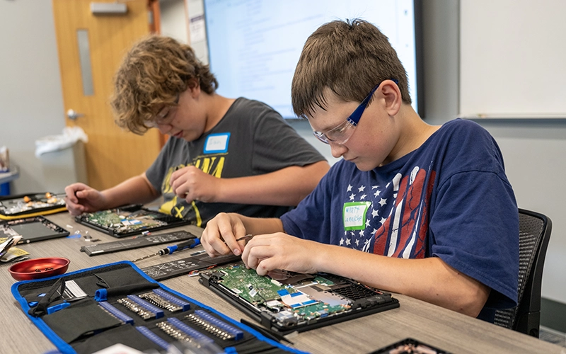 Two campers work on simulation motherboards.