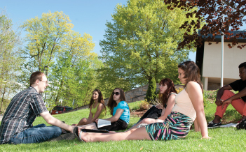 A professor leads an outdoor class while students sit on the lawn,