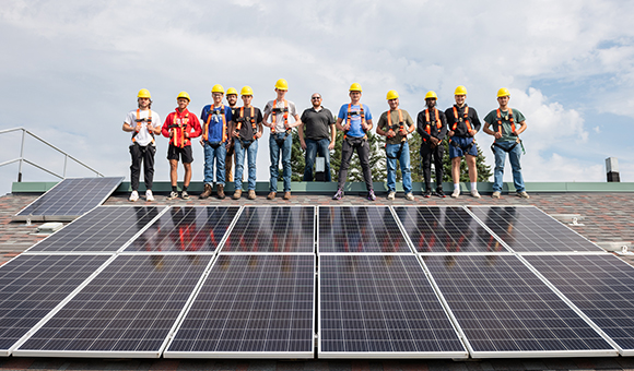 Students stand in a group at the top of the solar training roof.