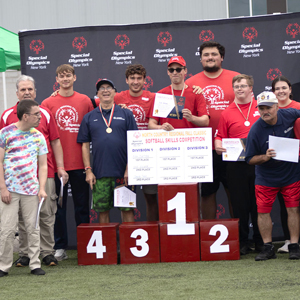 Special Olympics and SUNY Canton athletes gather around the award podium outside Roos House.